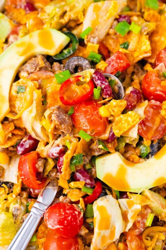 Close shot of taco salad with tomatoes, beans, cheese, avocado, and chips.
