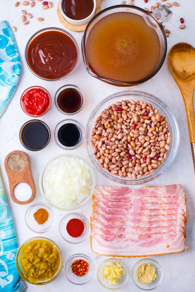 Overhead shot of instant pot baked beans ingredients in bowls on a white surface.