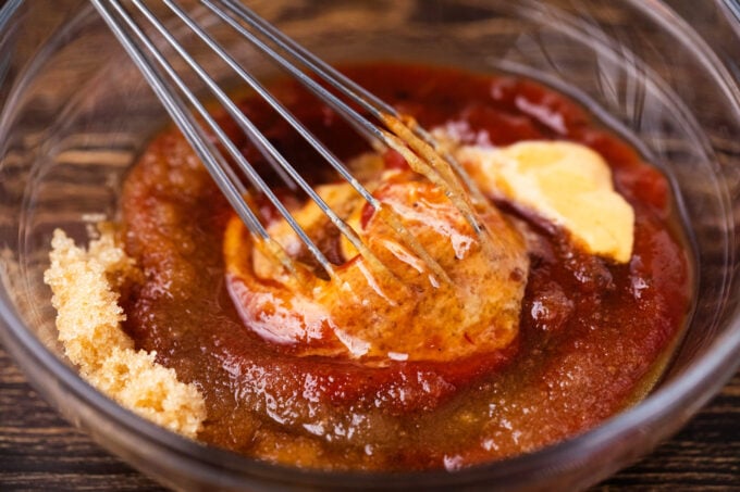 Whisking meatloaf glaze ingredients in a bowl.