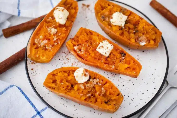 microwaved sweet potato halves on a serving plate topped with butter