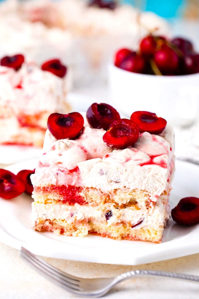 A slice of no bake cherry amaretto tiramisu topped with fresh cherries and cherry sauce.