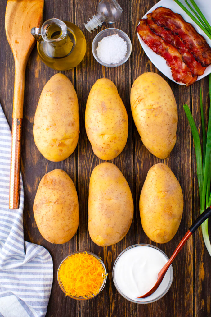 Overhead shot of oven baked potatoes ingredients arranges on a wooden table.