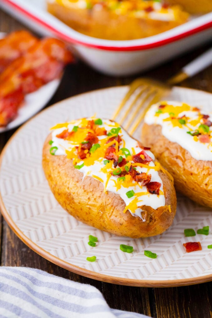 Oven baked potatoes topped with sour cream, cheese, and chopped bacon.