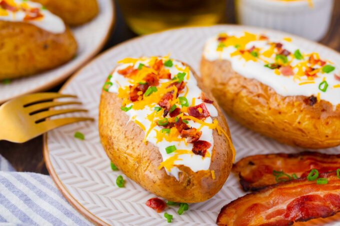 Oven baked potatoes topped with sour cream, cheese, chives, and chopped bacon.