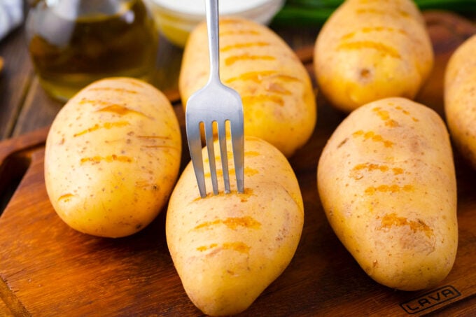 Piercing whole potatoes with a fork.