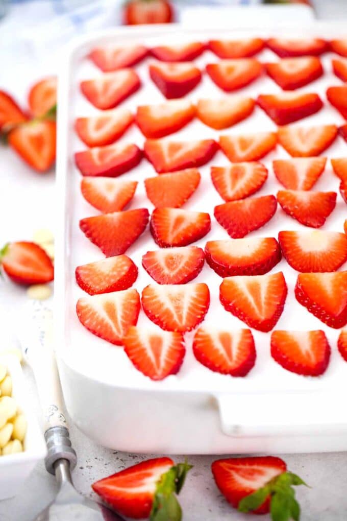 homemade strawberry poke cake topped with fresh strawberries