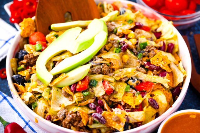 A bowl of taco salad topped with avocado slices.