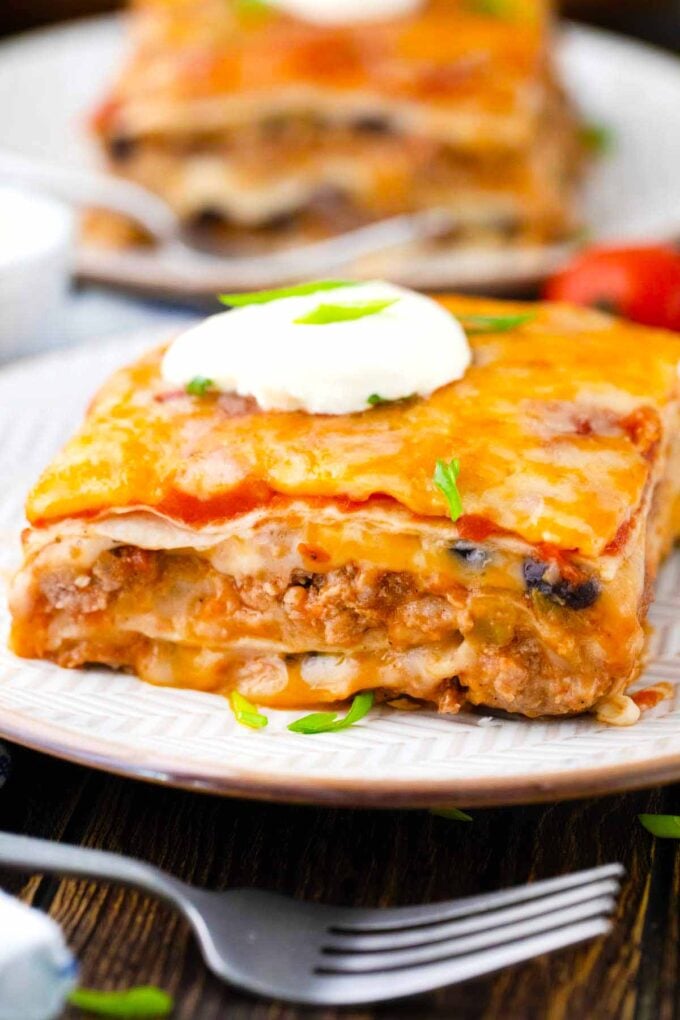 Taco lasagna slices topped with sour cream.