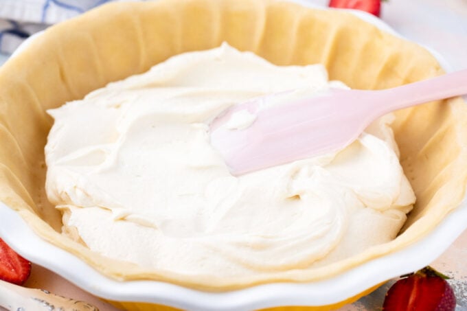 Adding cheesecake batter to pie crust.