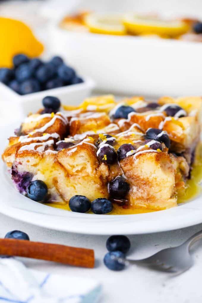 a slice of blueberry french toast casserole in syrup and topped with fresh blueberries