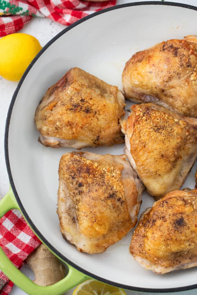 Browned chicken thighs in a skillet.
