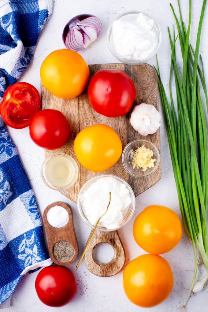 Overhead shot of creamy tomato salad ingredients in bowls on a table.
