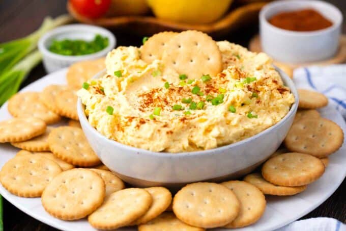 homemade deviled eggs dip topped with paprika and chives served with crackers