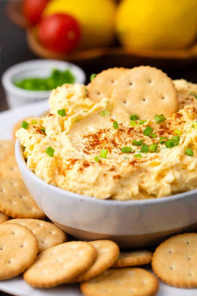 a bowl of deviled eggs dip topped with paprika and chives