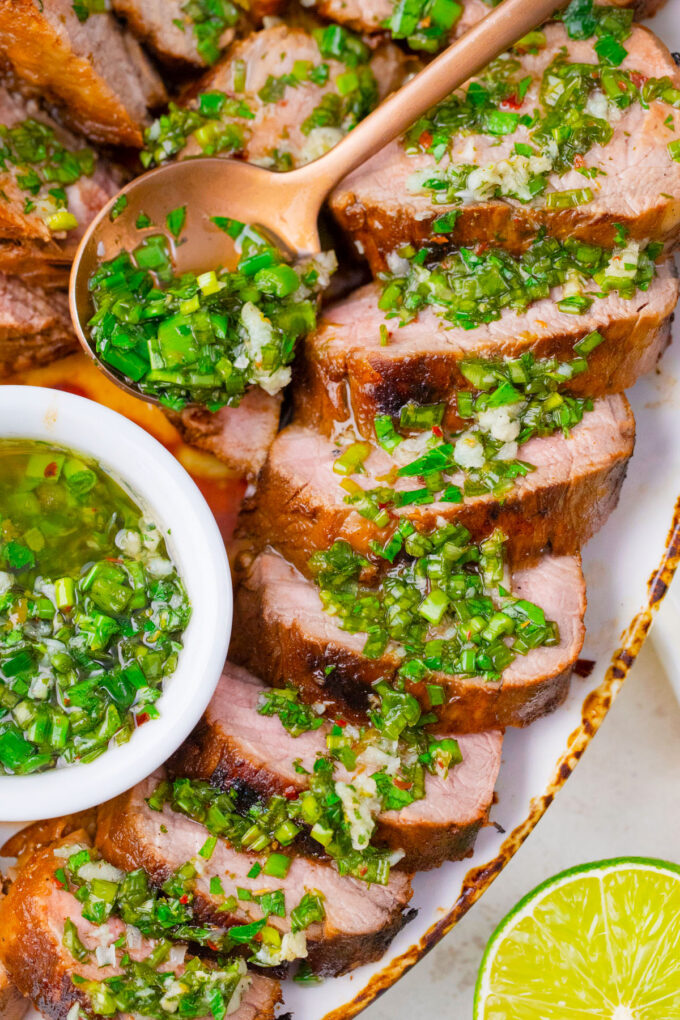 Grilled pork tenderloin served with herby garlic sauce.