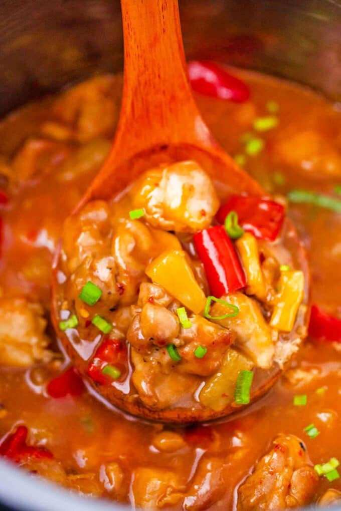 a ladle of instant pot sweet and sour chicken with pineapple and red pepper pieces