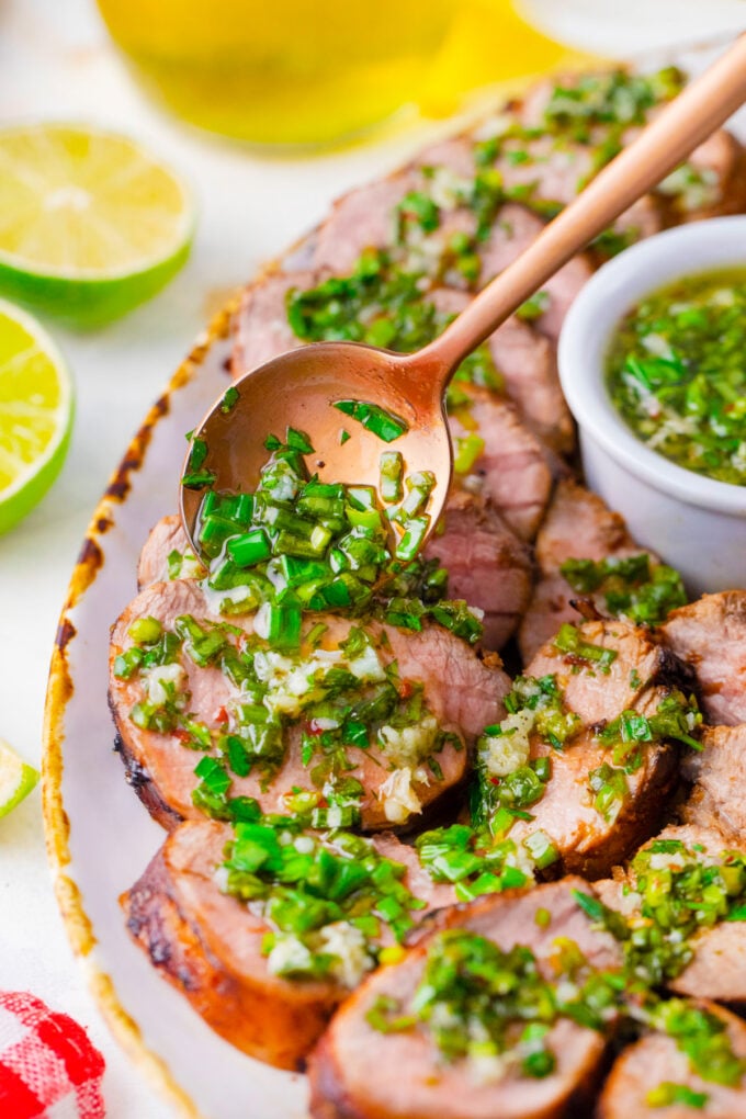 Serving grilled pork tenderloin with parsley garlic sauce.