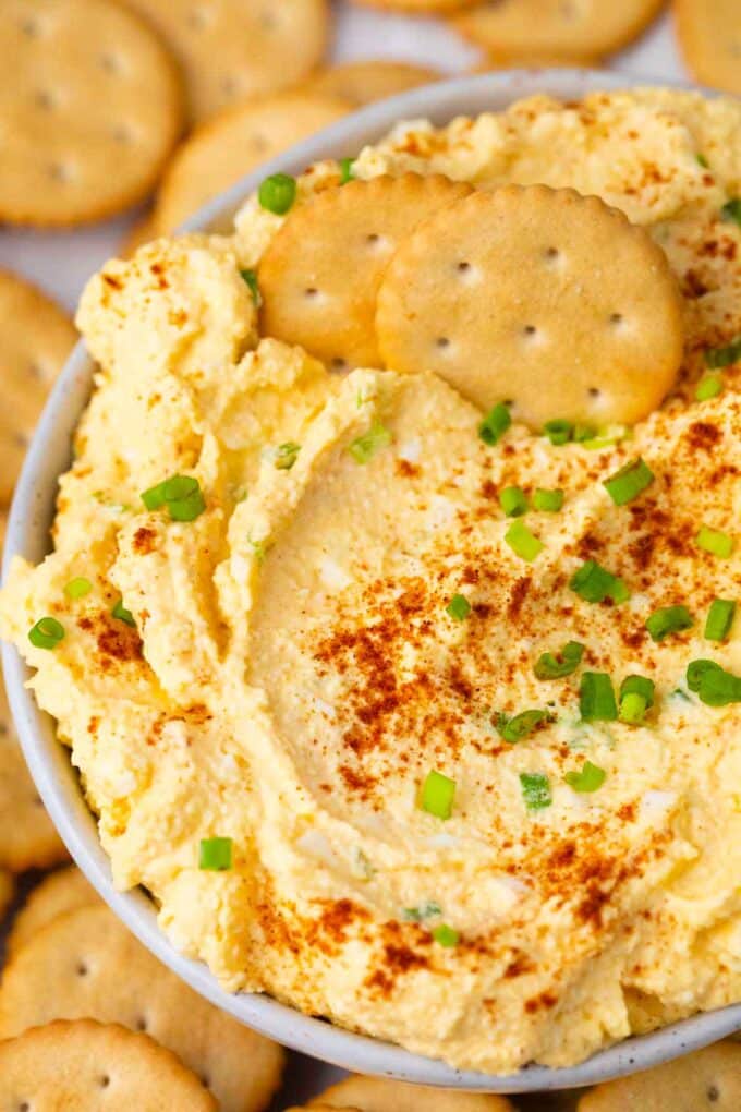 a bowl of homemade deviled eggs dip topped with paprika and chives