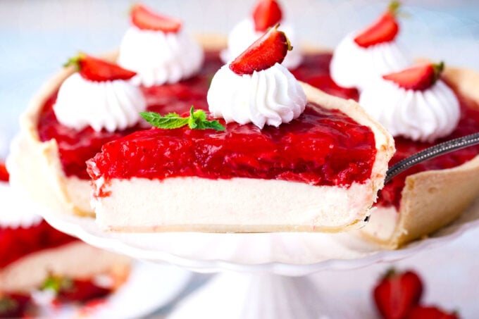 Sliced strawberry cheesecake pie on a cake stand.