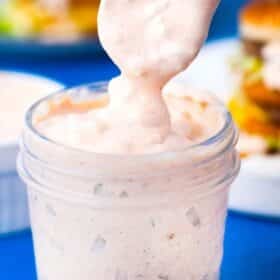 homemade thousand island dressing dripping of a spoon into a jar