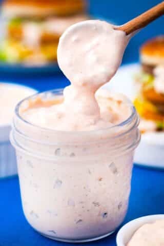 homemade thousand island dressing dripping of a spoon into a jar