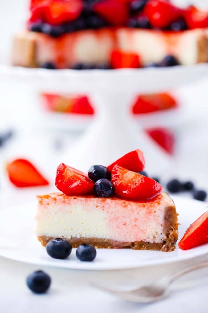 a slice of instant pot cheesecake topped with berries and berry sauce