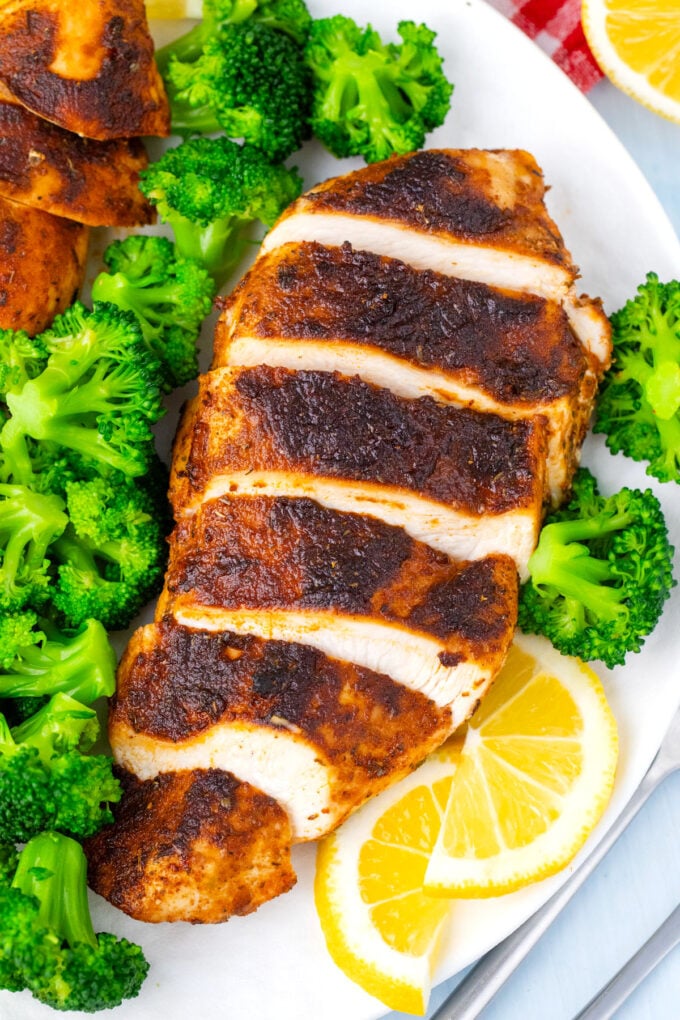 Sliced blackened chicken served with broccoli.