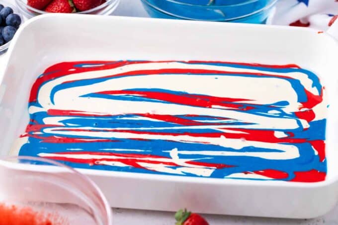 Red, white, and blue poke cake batter in a 9x13 pan.