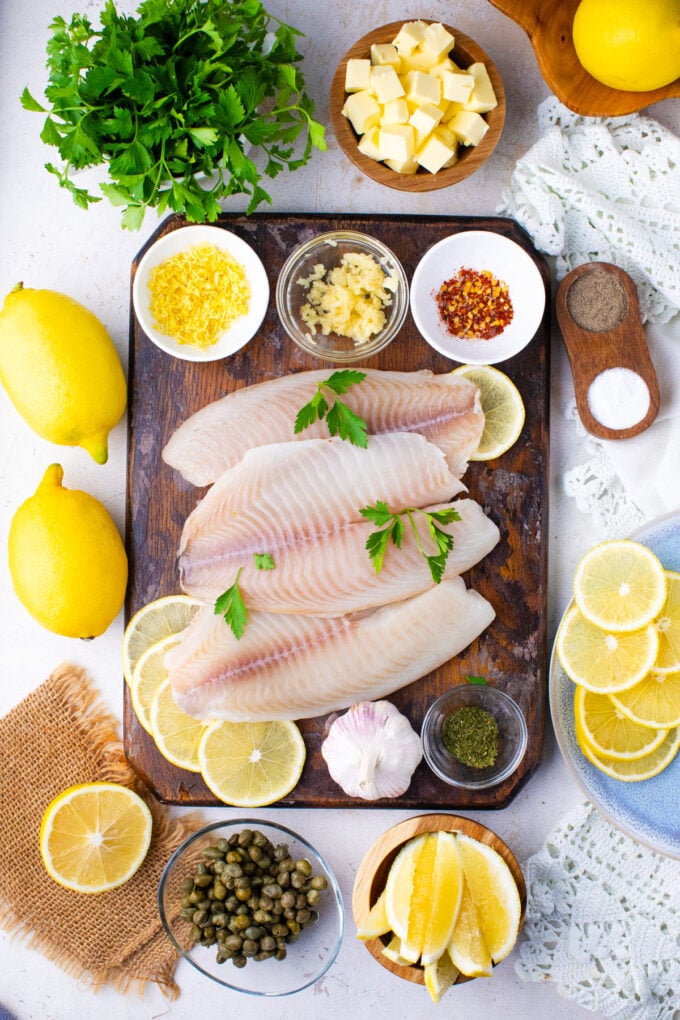 Overhead shot of lemon butter tilapia ingredients arranged on a cutting board.