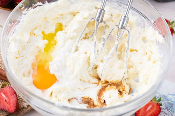 Whisking cheesecake batter ingredients in a bowl.