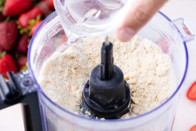 Adding water to flour and butter in a food processor.