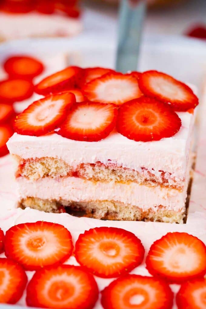 A slice of no bake strawberry tiramisu topped with fresh strawberries on a serving spatula.