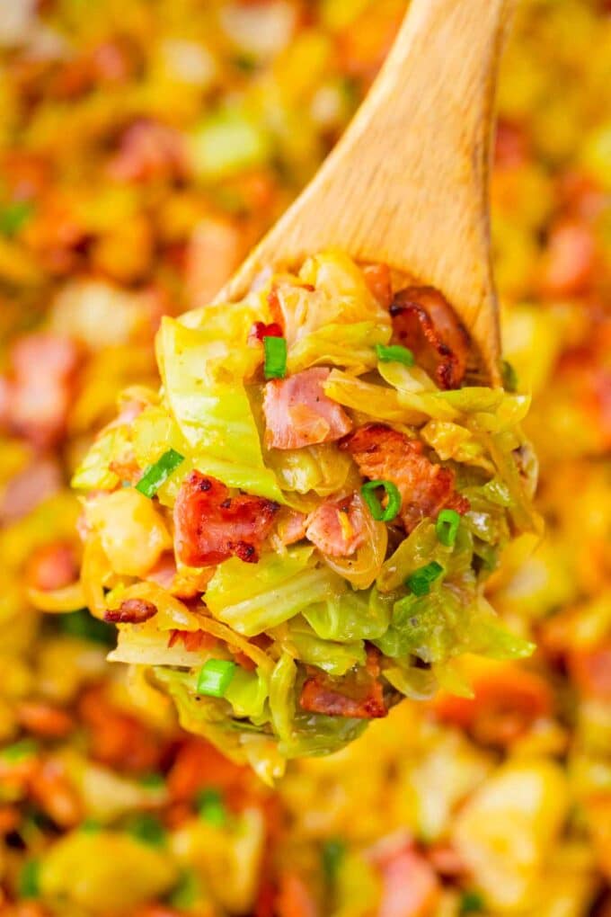 A serving spoon of bacon fried cabbage.