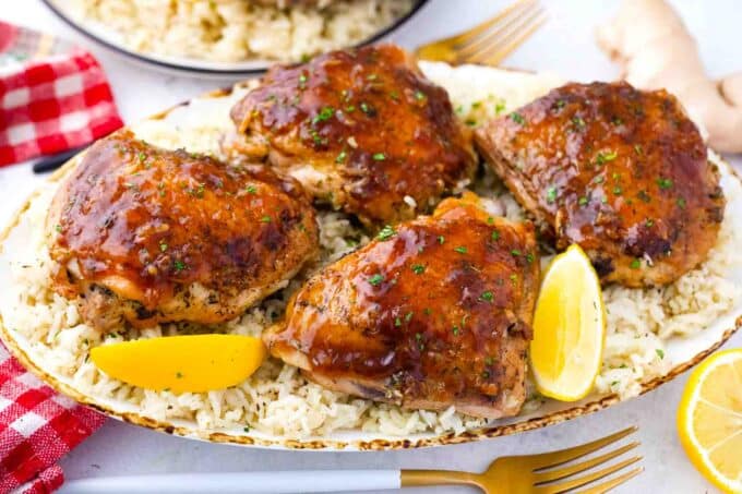 honey garlic chicken and rice on a serving plate with lemon wedges