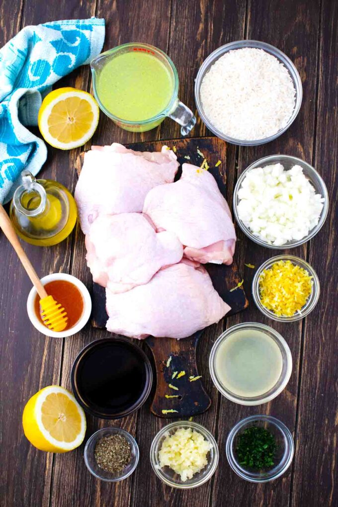 one pan italian chicken and rice ingredients in bowls on a wooden table with chicken thighs arranged on a cutting board