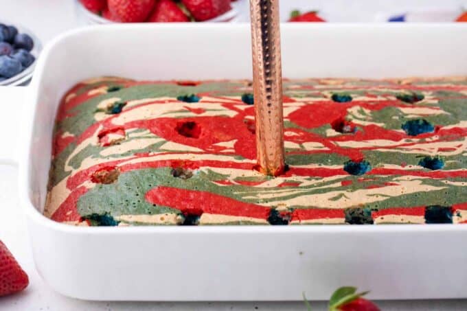 Poking holes into a patriotic poke cake.