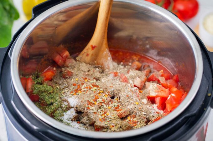 Adding ingredients to the instant pot to make spaghetti sauce.