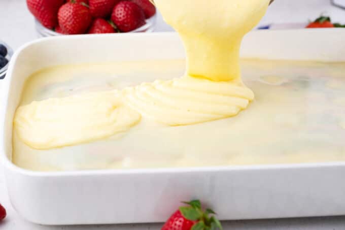 Topping patriotic poke cake with vanilla pudding.