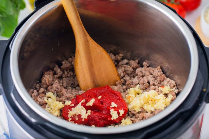 Sautéing beef, garlic and tomato paste in the instant pot.