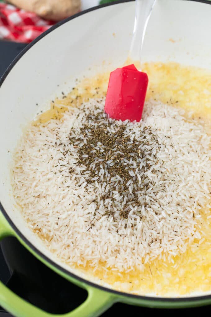 Sauteing dry rice and seasoning in a pan.