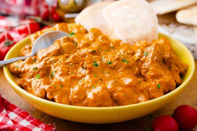 a plate of slow cooker butter chicken with a few pieces of naan