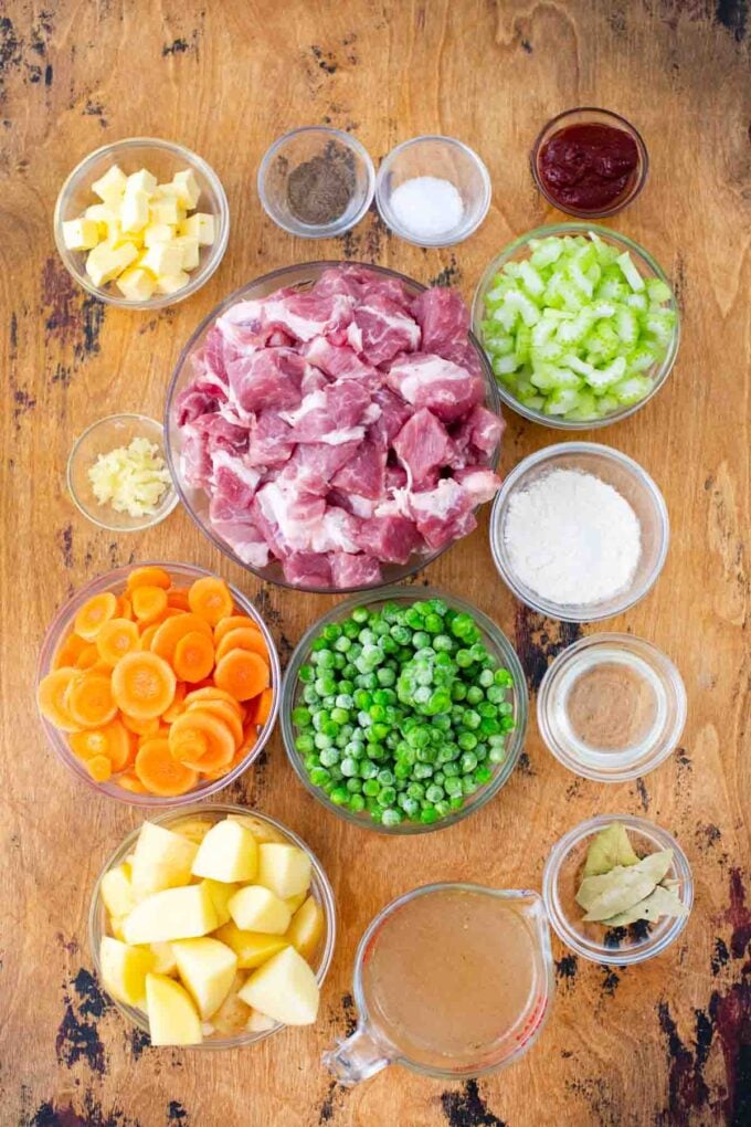 slow cooker pork stew ingredients in bowls on a wooden table