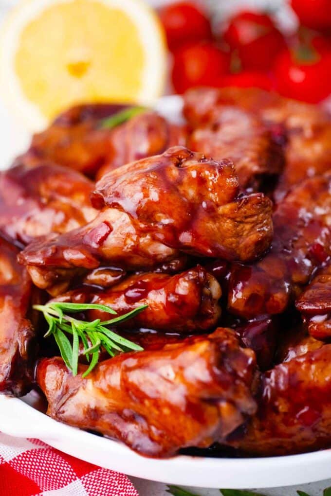 sticky sticky red wine glazed wings on a serving plate with some rosemary sprigs