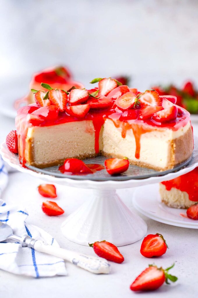 sliced strawberry cheesecake topped with strawberry sauce topping and fresh strawberries