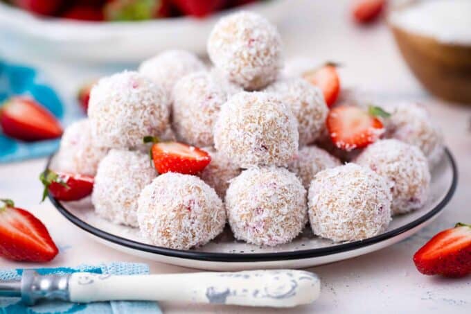 a plate of strawberry coconut truffles covered in shredded coconut