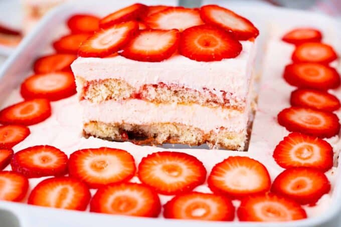 Lifting a slice of strawberry tiramisu on a serving spatula.