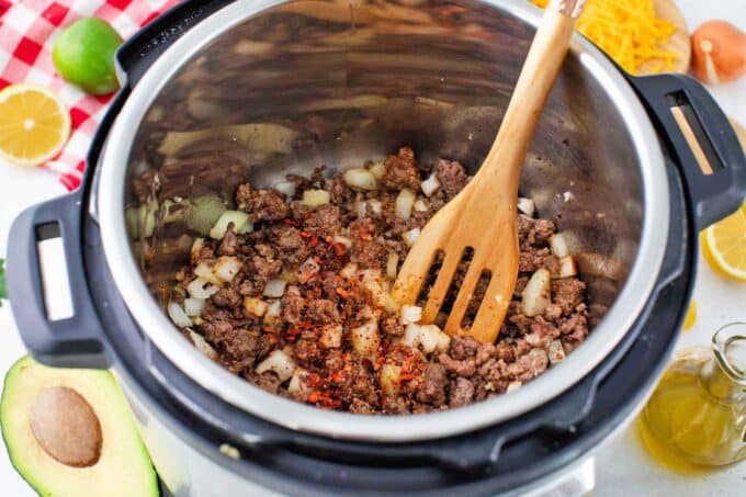 cooking ground beef in the instant pot with onion, garlic, and taco seasoning