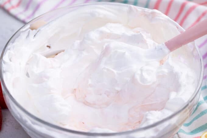 Folding whipped cream into a bowl of mascarpone and cream cheese frosting.
