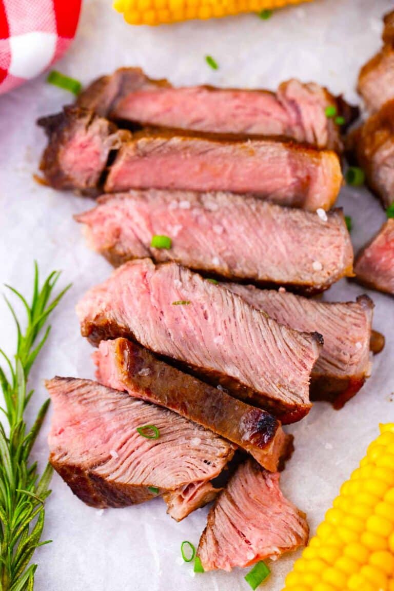 Overhead shot of juicy, sliced Asian style grilled rib-eye steak on a cutting board.