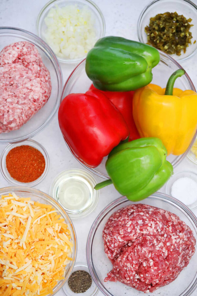 Overhead shot of Mexican stuffed peppers ingredients in bowls on a white table.